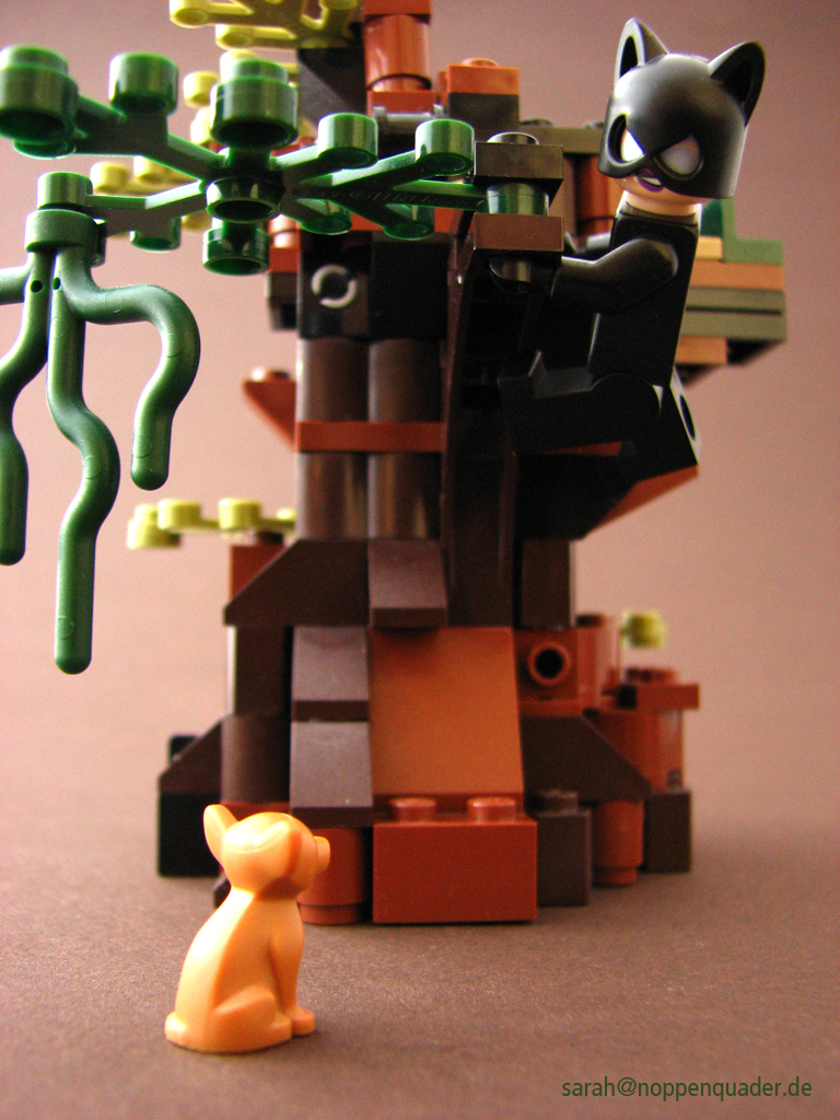 Lego Minifig Catwoman schwingt sich mit Blick auf einen Chihuahua auf den nächsten Baum